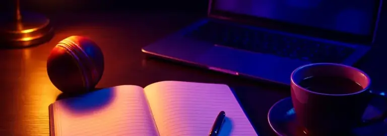 Tidy desk with a laptop and an open notebook in warm lamp light